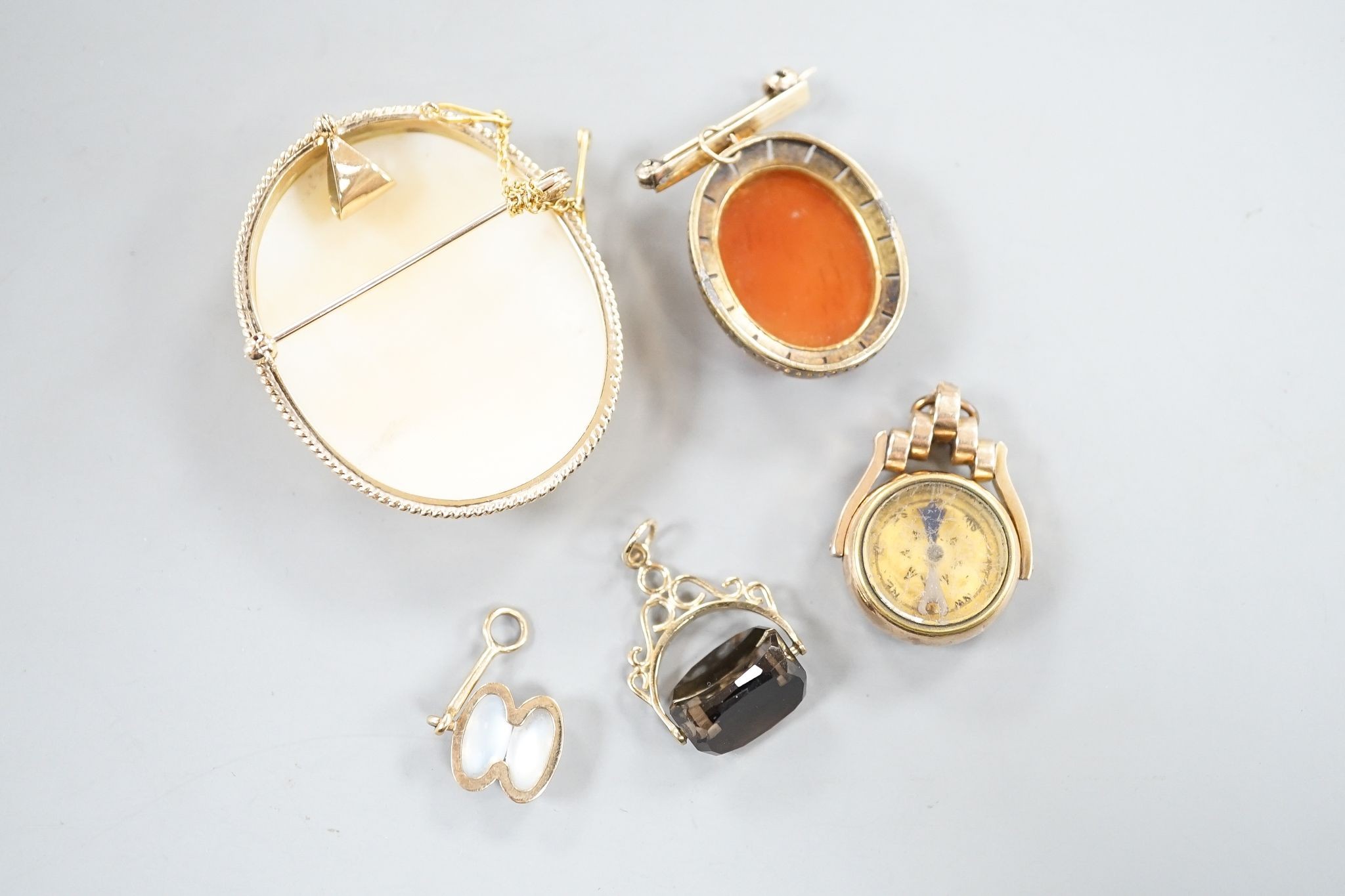 A modern 9ct gold mounted oval cameo shell brooch, 46mm, gross 16.4 grams, one other hardstone and split pearl set pendant brooch, a late Victorina 9ct spinning compass fob and two other items.